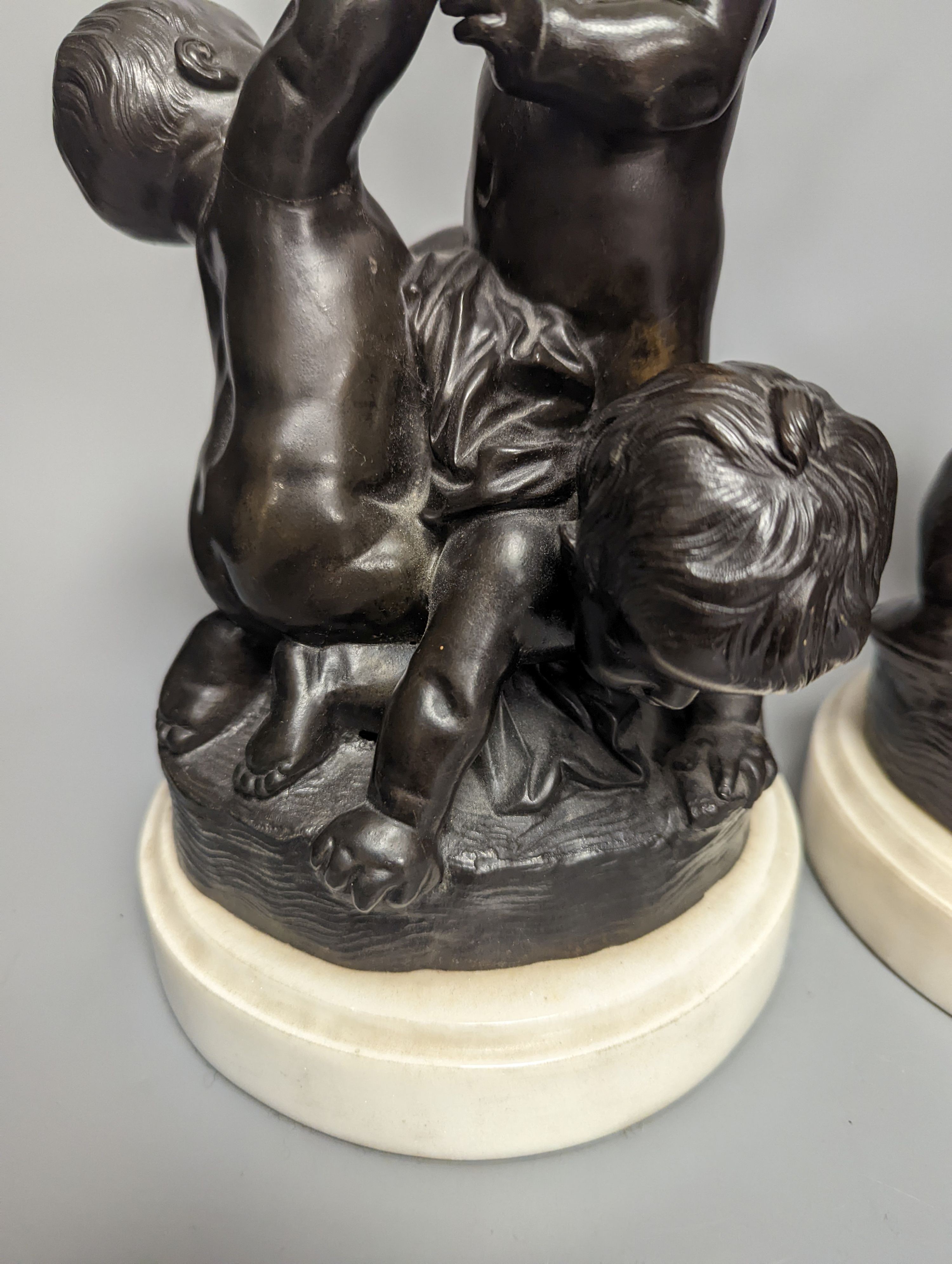 A pair of bronze figure groups, trio of putto, on white marble plinths, tallest 26cm